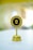 A golden trophy with a round black and gold plaque mounted on top featuring the text 'EMPLOYEE OF THE MONTH FEBRUARY-2021' placed on a light-colored surface. The background is blurred, making the trophy the focal point of the image.