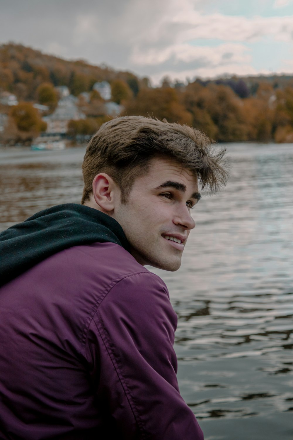 man in purple and black jacket near body of water during daytime