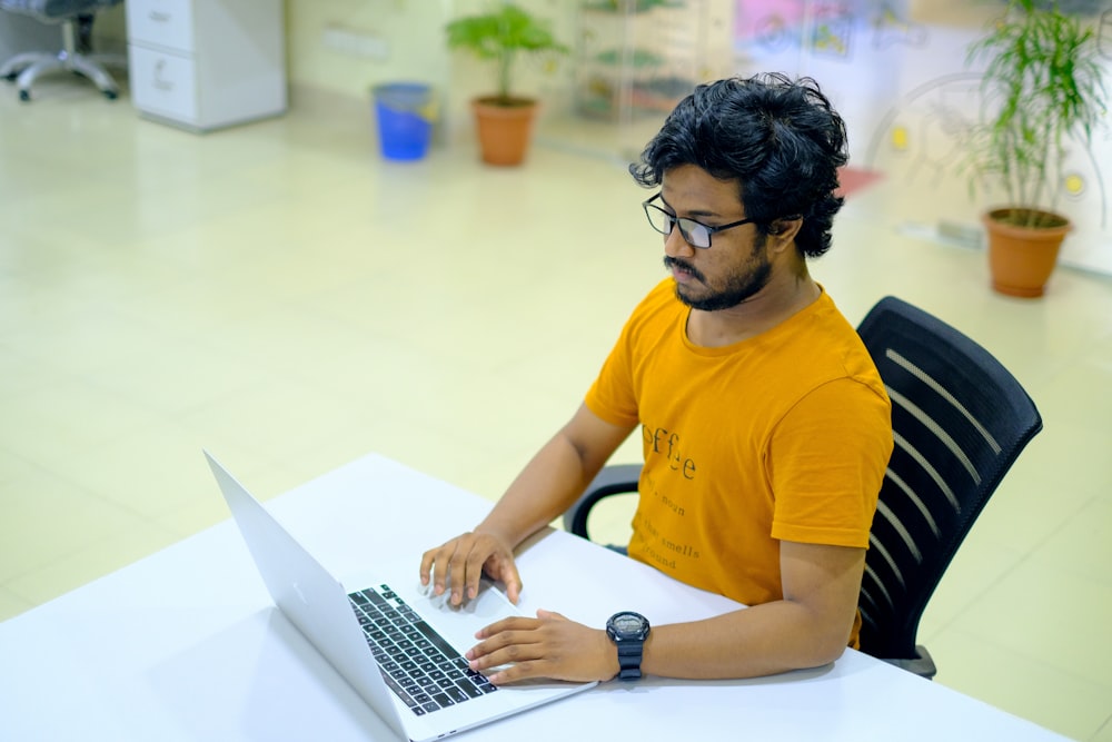 man in yellow crew neck t-shirt using macbook pro