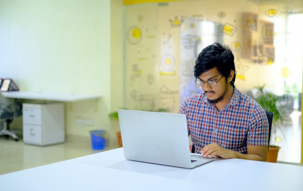 woman in blue and white checkered shirt using macbook