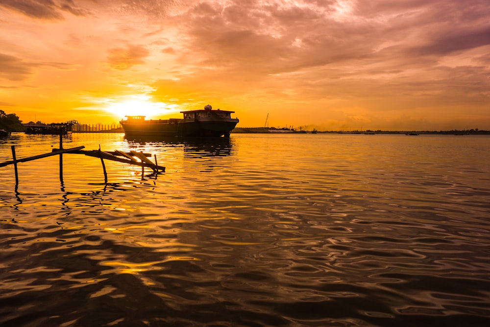 silhouette de bateau sur la mer pendant le coucher du soleil