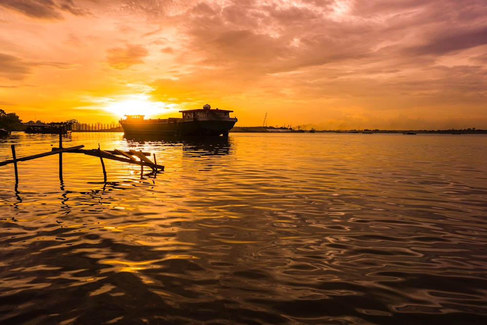 silhouette of boat on sea during sunset