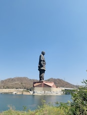 man in black jacket statue near body of water during daytime