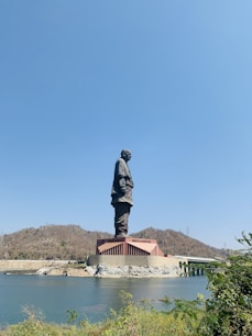man in black jacket statue near body of water during daytime