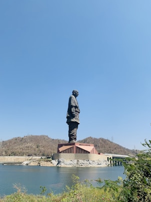 man in black jacket statue near body of water during daytime