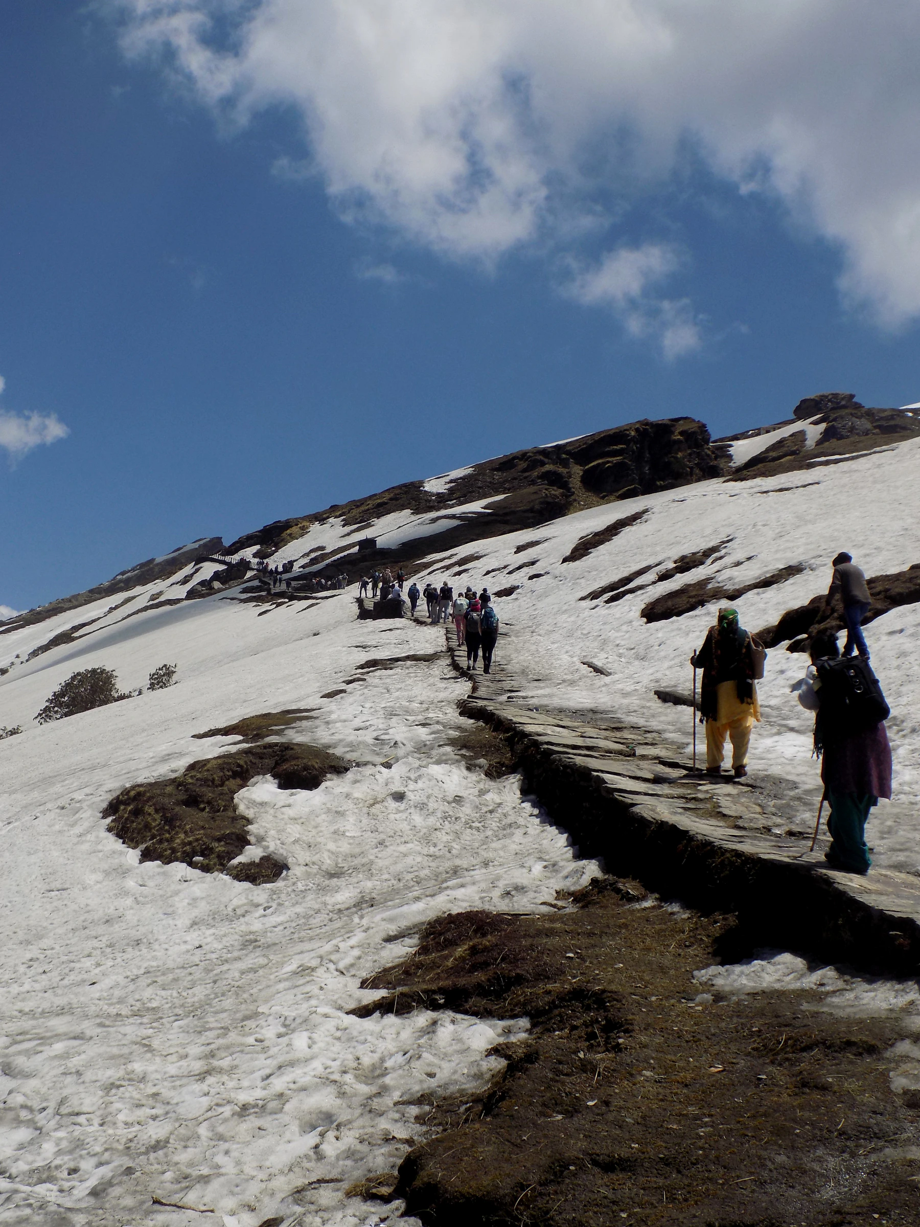 Trekkers crossing a dramatic Himalayan snow trail