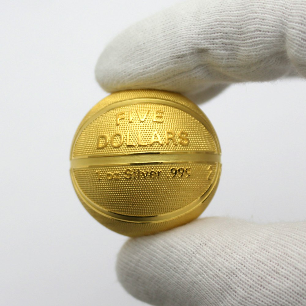 gold round coin on white textile