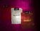 Three folded ribbed shirts are neatly arranged on a bright magenta furry surface. Each shirt is labeled with a 'MANGO' brand tag. The shirts are in red, white, and brown colors, with the word 'MANGO' printed on them in contrasting thread colors.