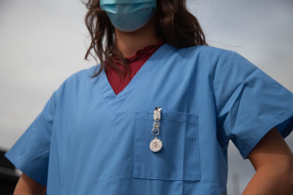 Healthcare worker in scrubs, protective goggles, and mask
