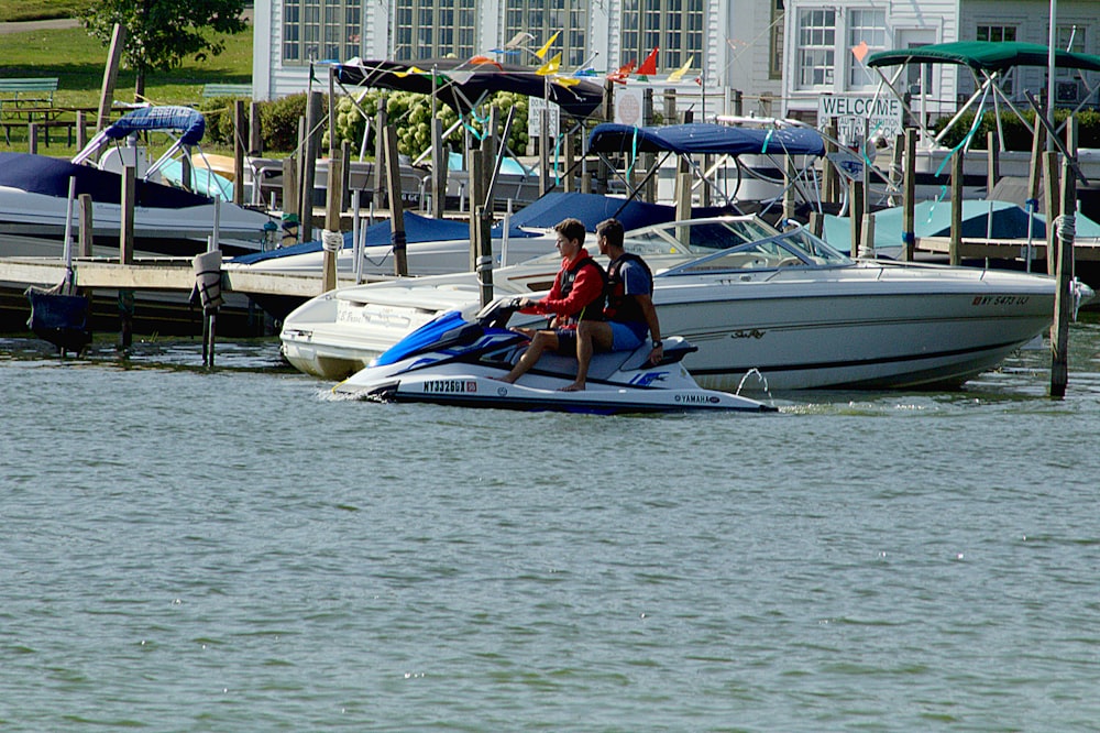 man in red shirt riding on white and blue boat during daytime