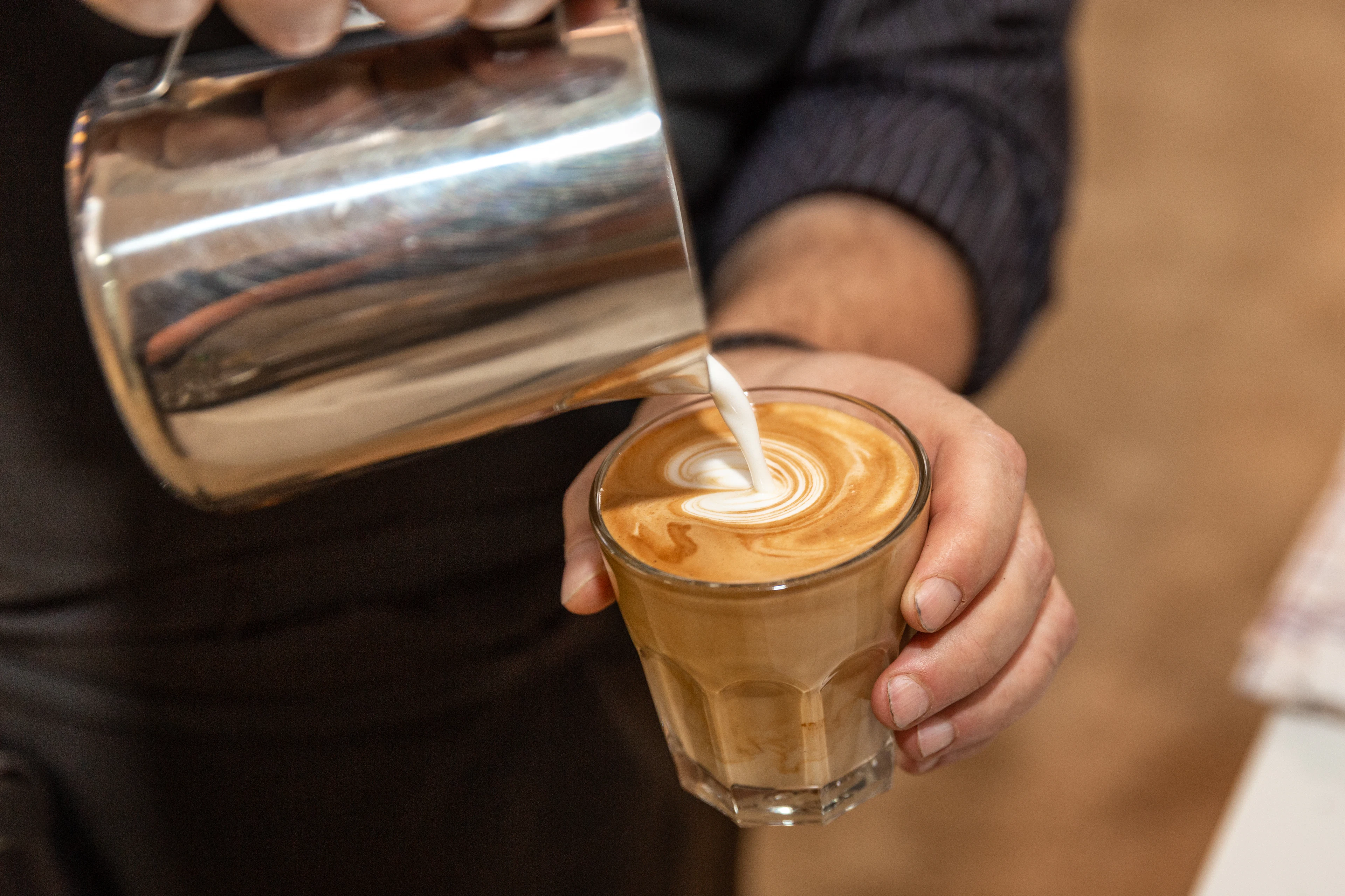 Barista pouring steamed milk into a cortado