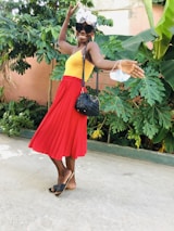 A joyful woman wearing a stylish dress and matching accessories, smiling outdoors.