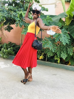 A joyful woman wearing a stylish dress and matching accessories, smiling outdoors.