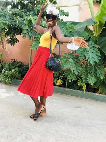 A vibrant photo of a woman joyfully wearing a bright yellow dress from Solara Moda, standing in a sunlit urban street.