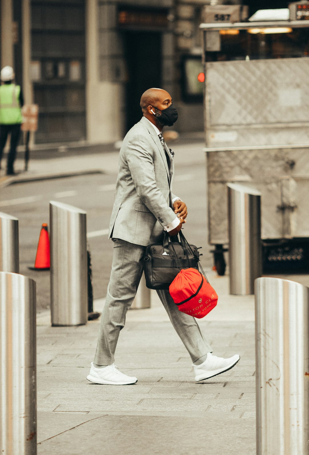 man in gray coat and brown pants with black backpack walking on sidewalk during daytime