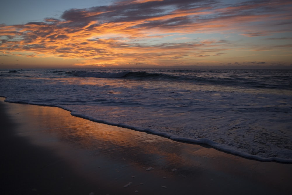 ocean waves crashing on shore during sunset