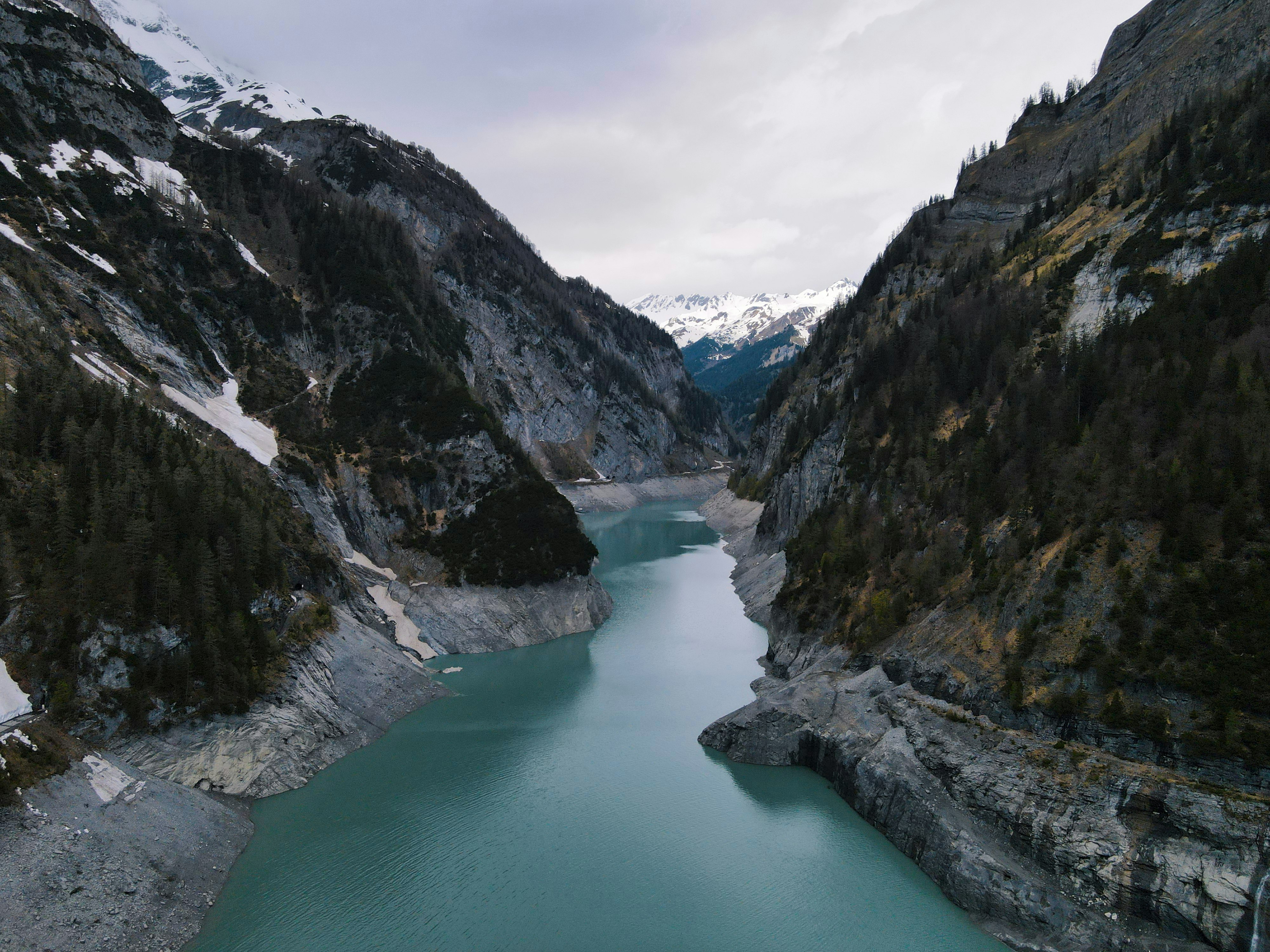 lake between mountains under cloudy sky during daytime