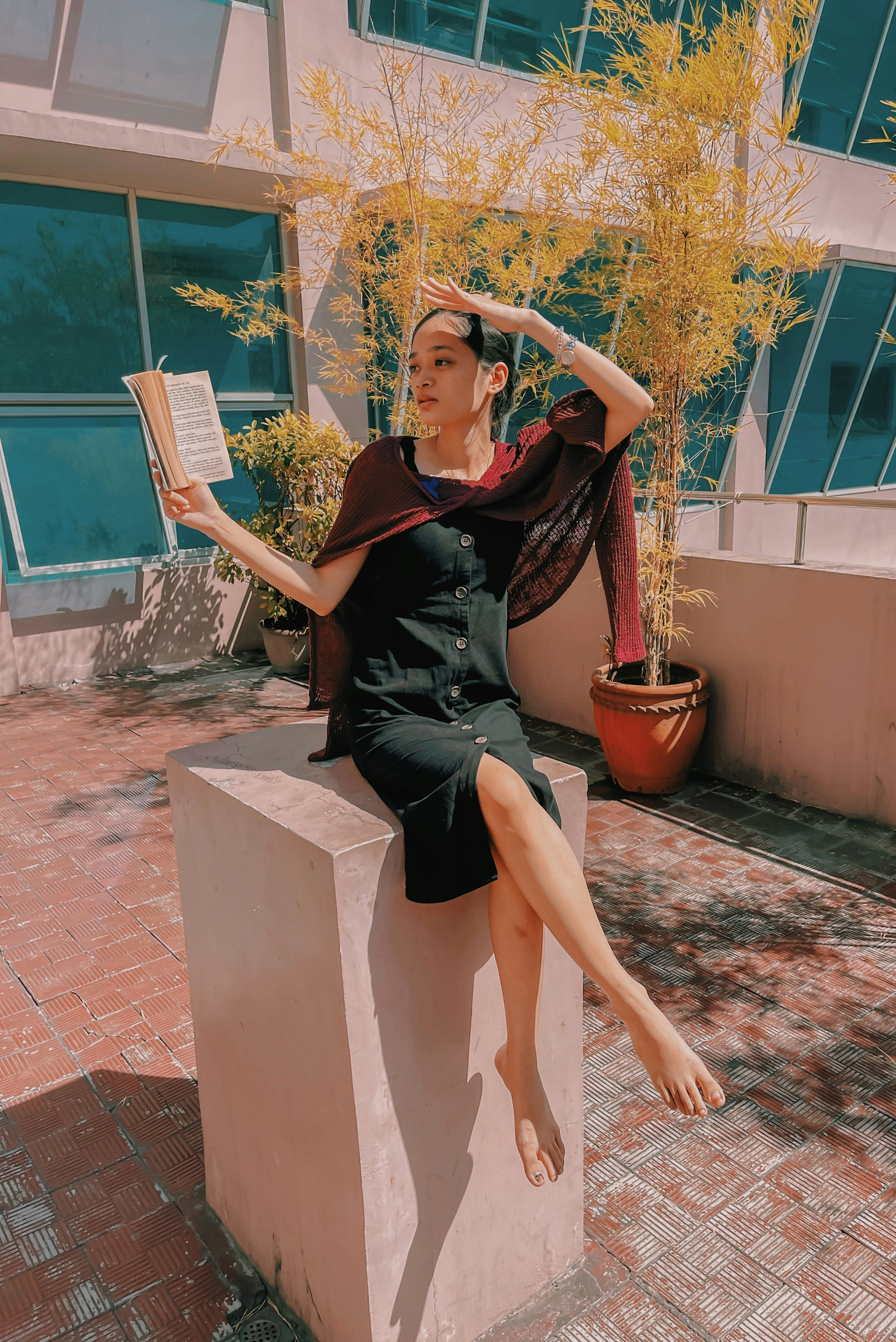 woman in black sleeveless dress sitting on brown concrete bench