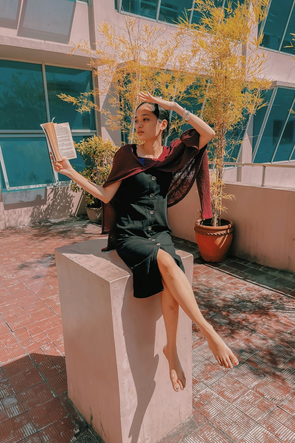 woman in black sleeveless dress sitting on brown concrete bench