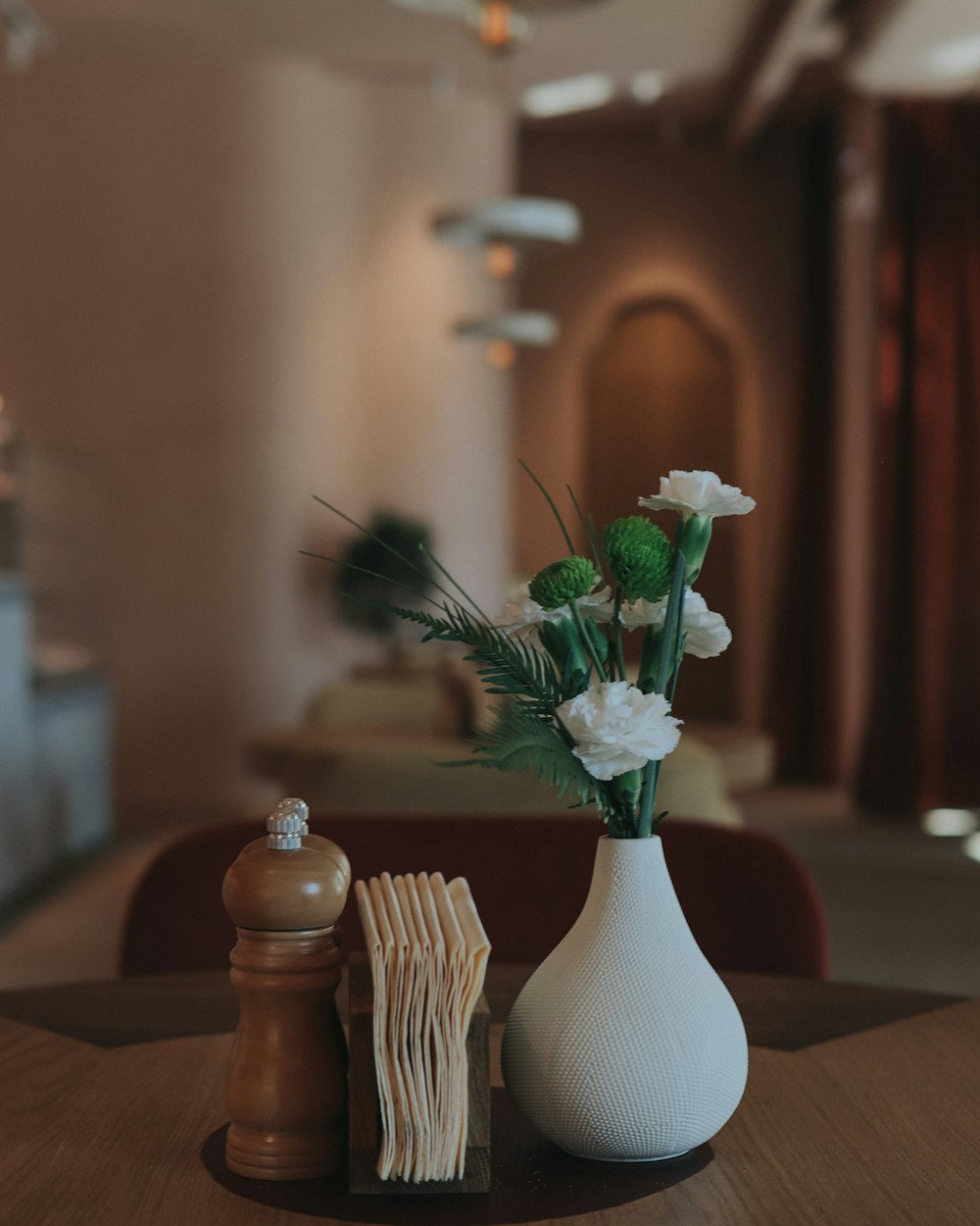 white flowers in white ceramic vase on brown wooden table