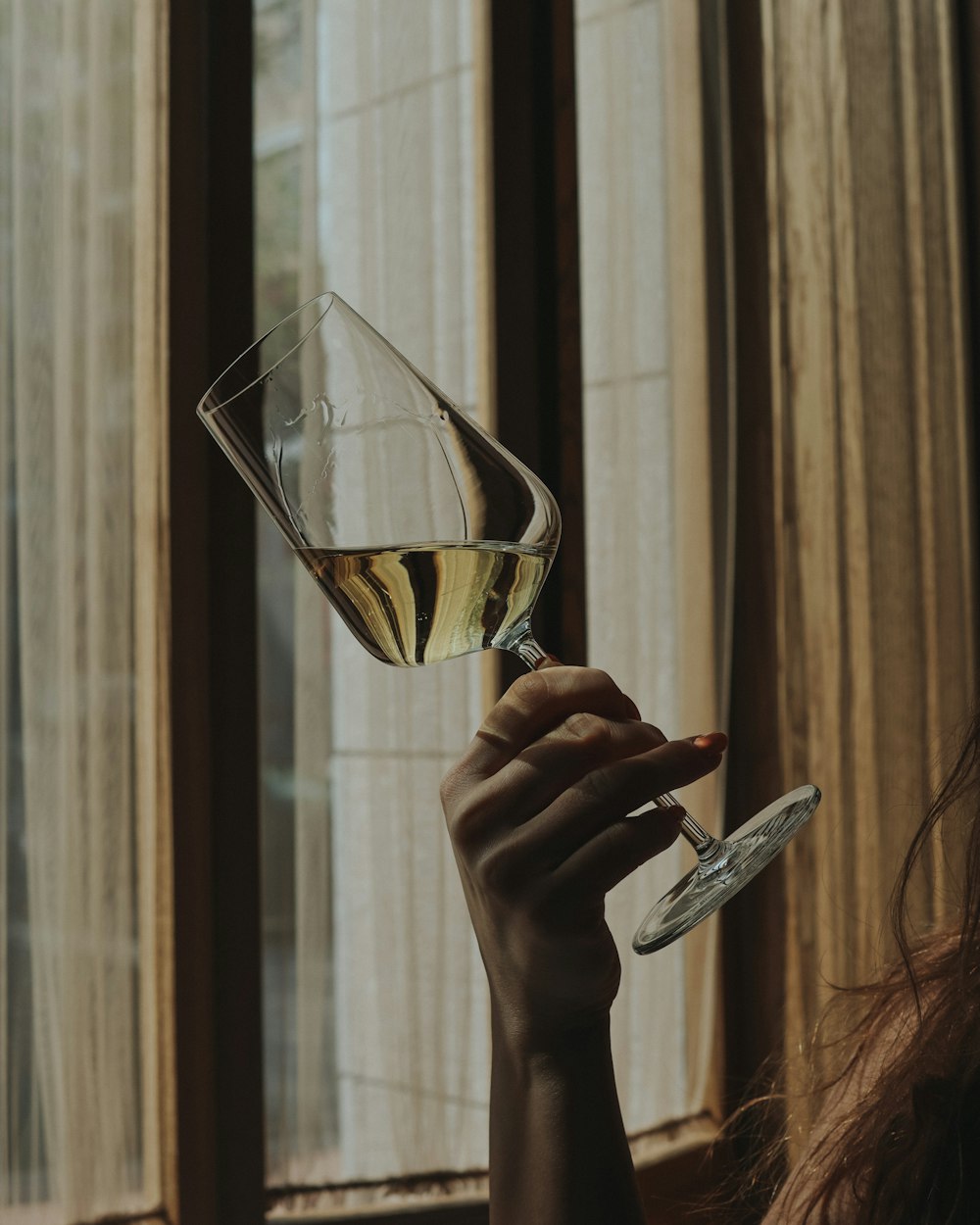pessoa segurando taça de vinho transparente