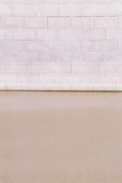 White wall tiles beside white wall. Water and brick texture