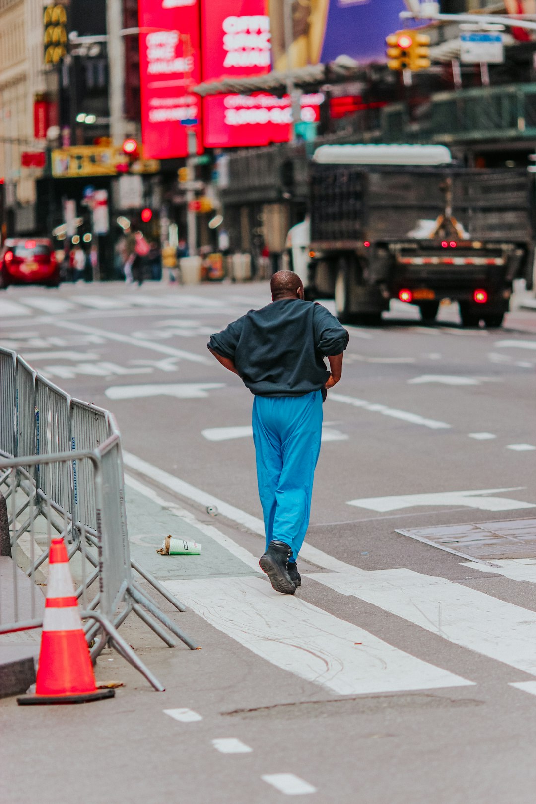 man in black hoodie and blue denim jeans walking on pedestrian lane during daytime