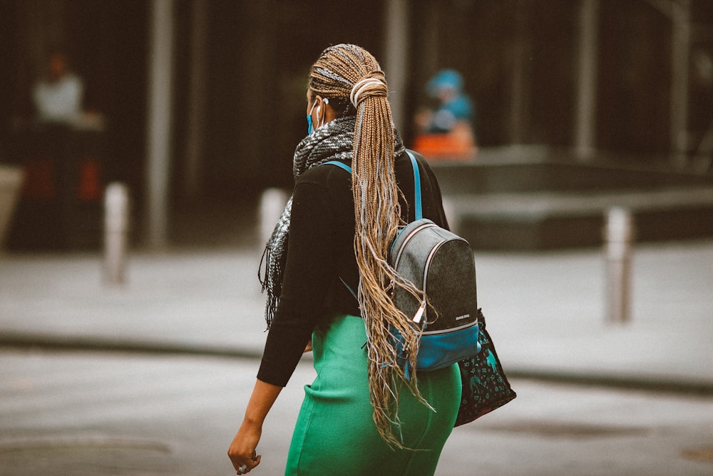 woman in black leather jacket and green skirt walking on street during daytime