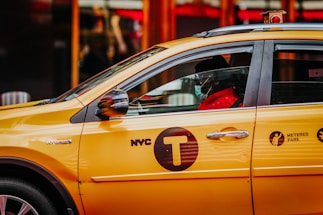 A friendly taxi driver standing by a yellow cab ready to help passengers.