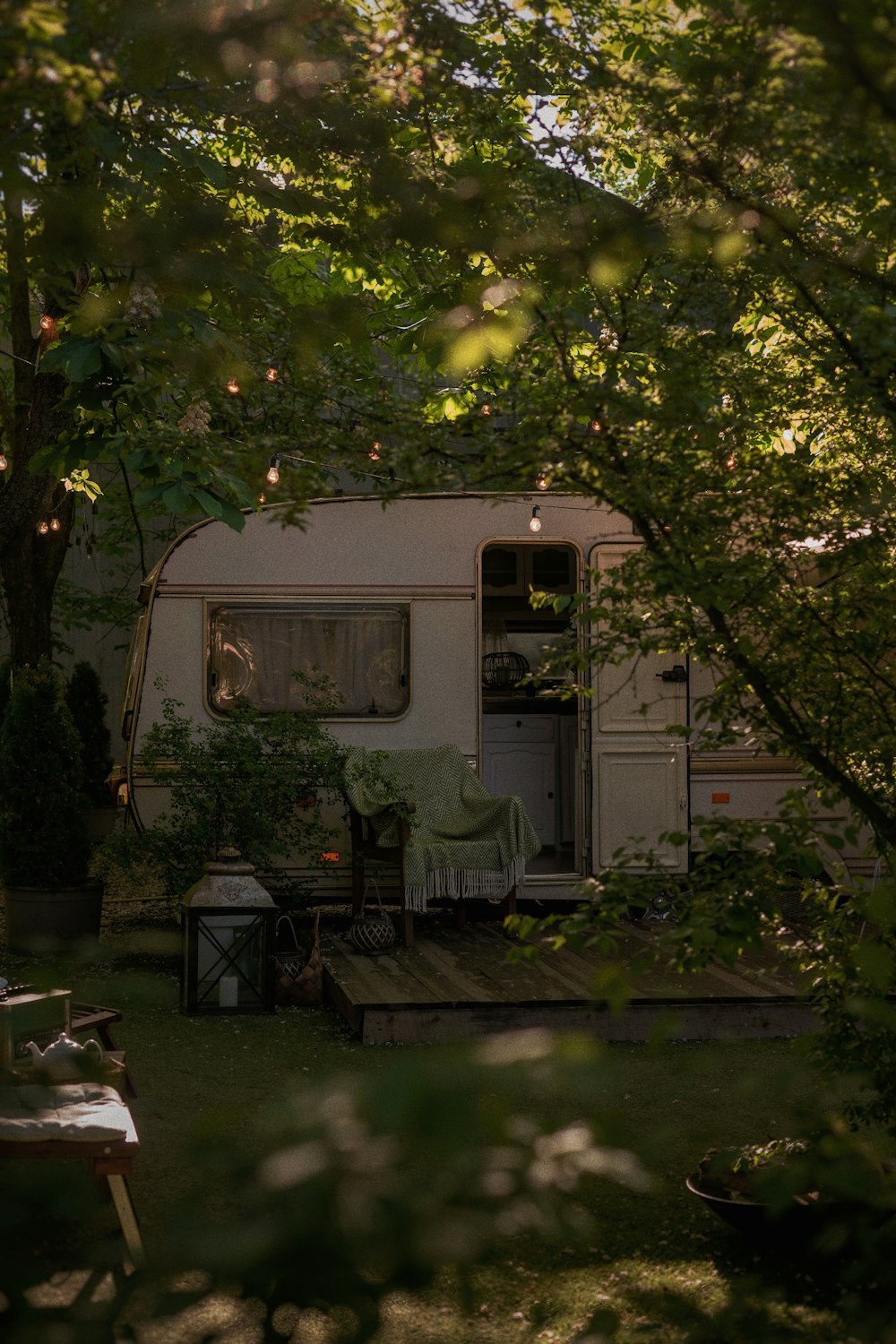 white and green rv trailer under green tree during daytime