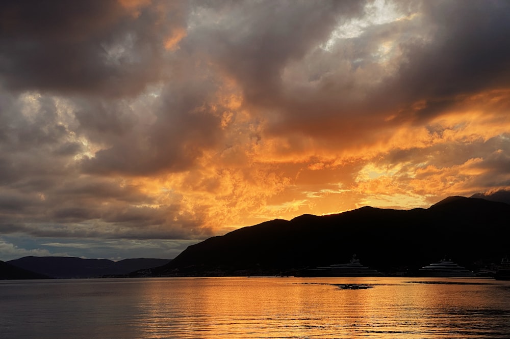 silhouette of mountain near body of water during sunset