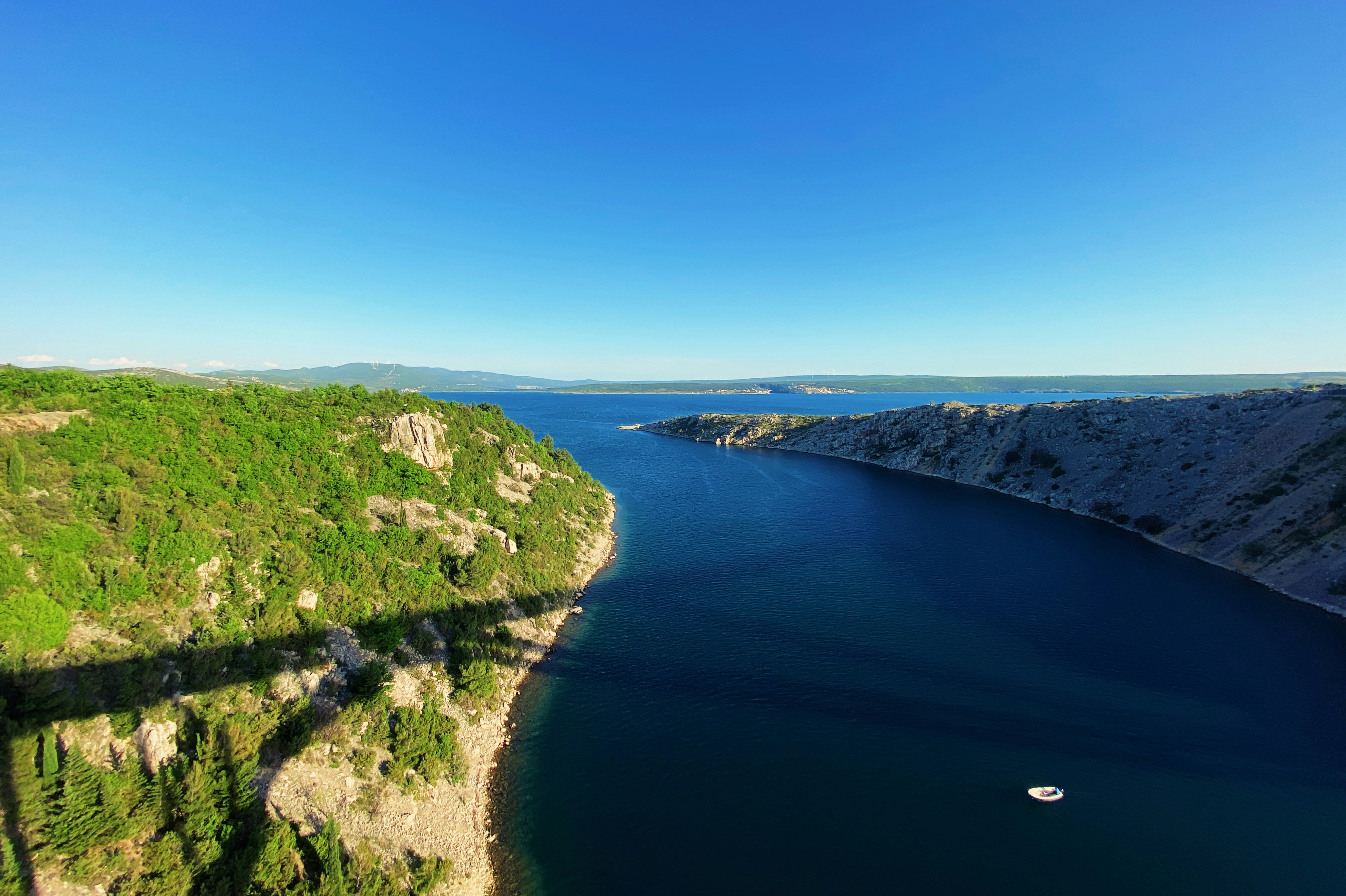 green grass field near lake under blue sky during daytime, 