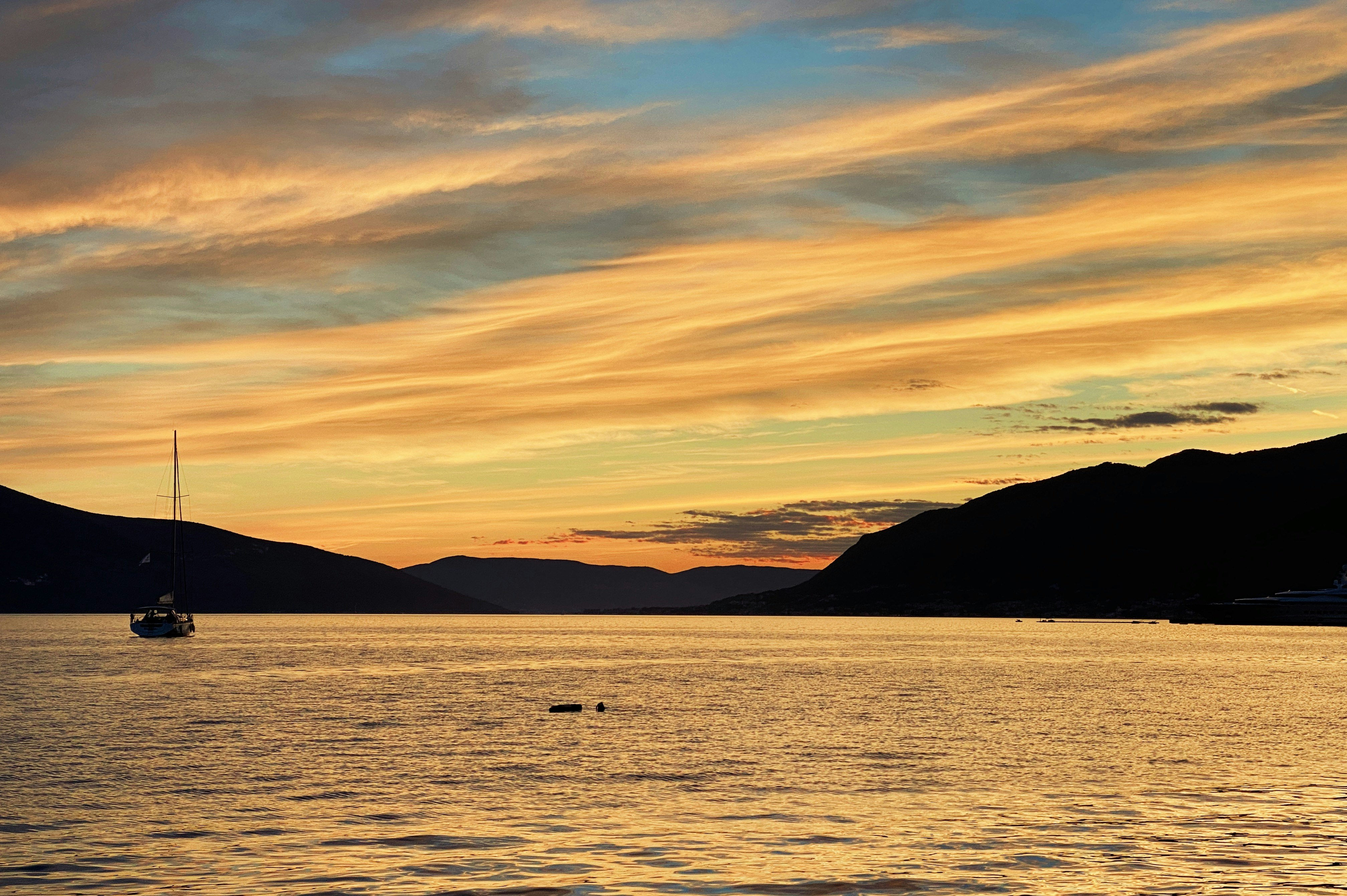 silhouette of mountain beside sea during sunset