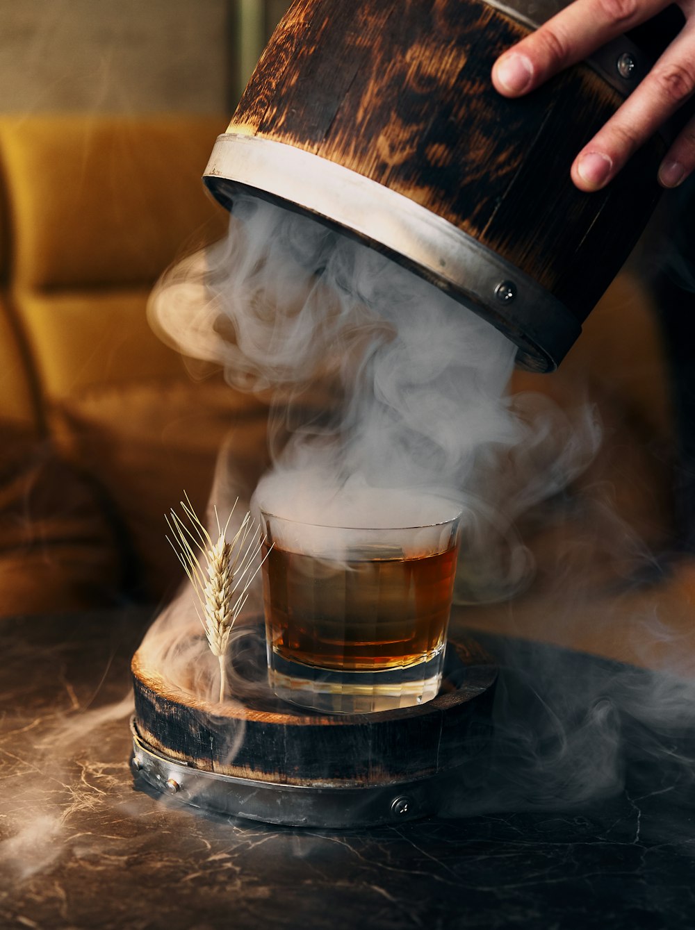 person pouring brown liquid on clear glass container