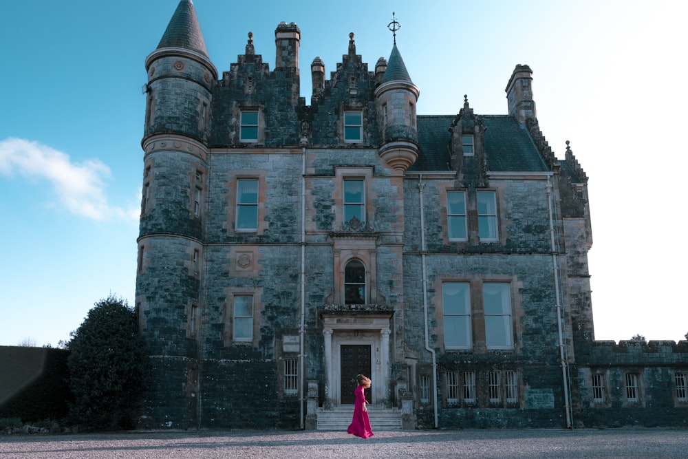 woman in red jacket standing in front of brown concrete building during daytime