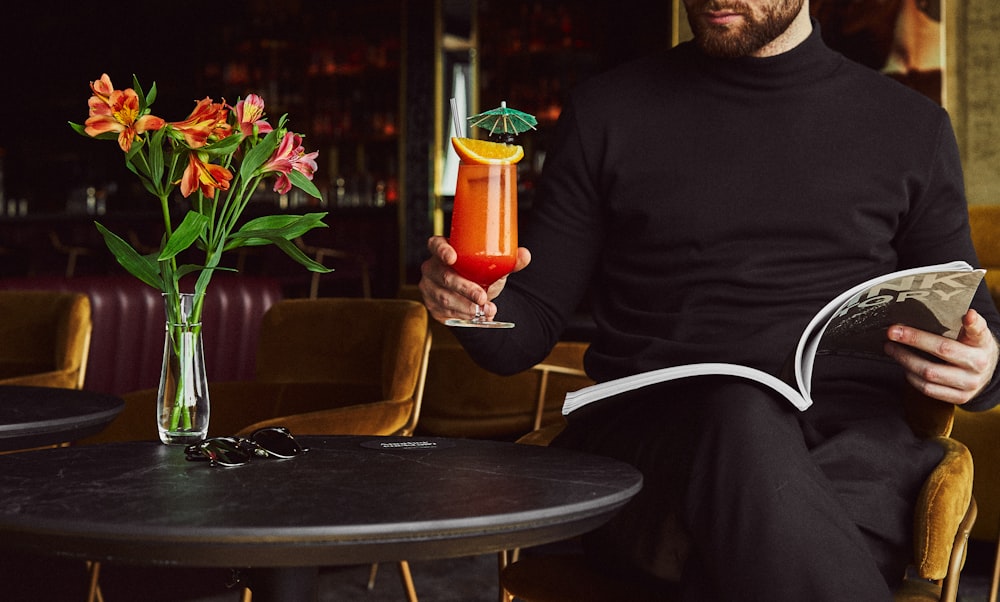 man in black crew neck long sleeve shirt holding orange and white plastic cup