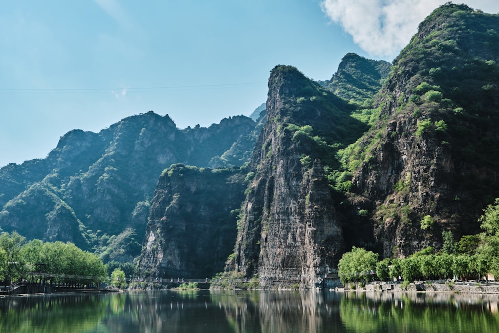 green and gray mountain beside body of water under blue sky during daytime