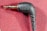 A close-up image of a black audio jack connector labeled with the brand 'RODE' against a textured red fabric background. The connector is at a right angle, and the metallic plug is visible.