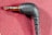 A close-up image of a black audio jack connector labeled with the brand 'RODE' against a textured red fabric background. The connector is at a right angle, and the metallic plug is visible.