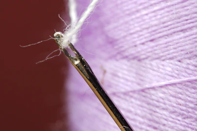 Close-up of a needle pulling thread through colorful fabric.