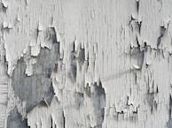 Technician pressure washing a weathered deck, revealing fresh wood beneath.