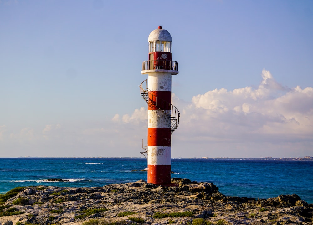 red and white lighthouse near body of water during daytime