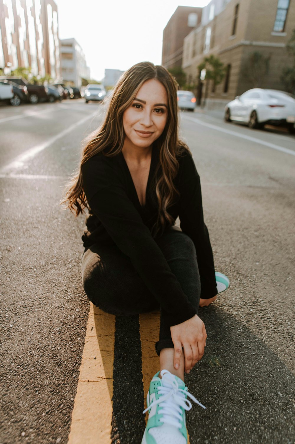 woman in black blazer and blue denim jeans sitting on road during daytime