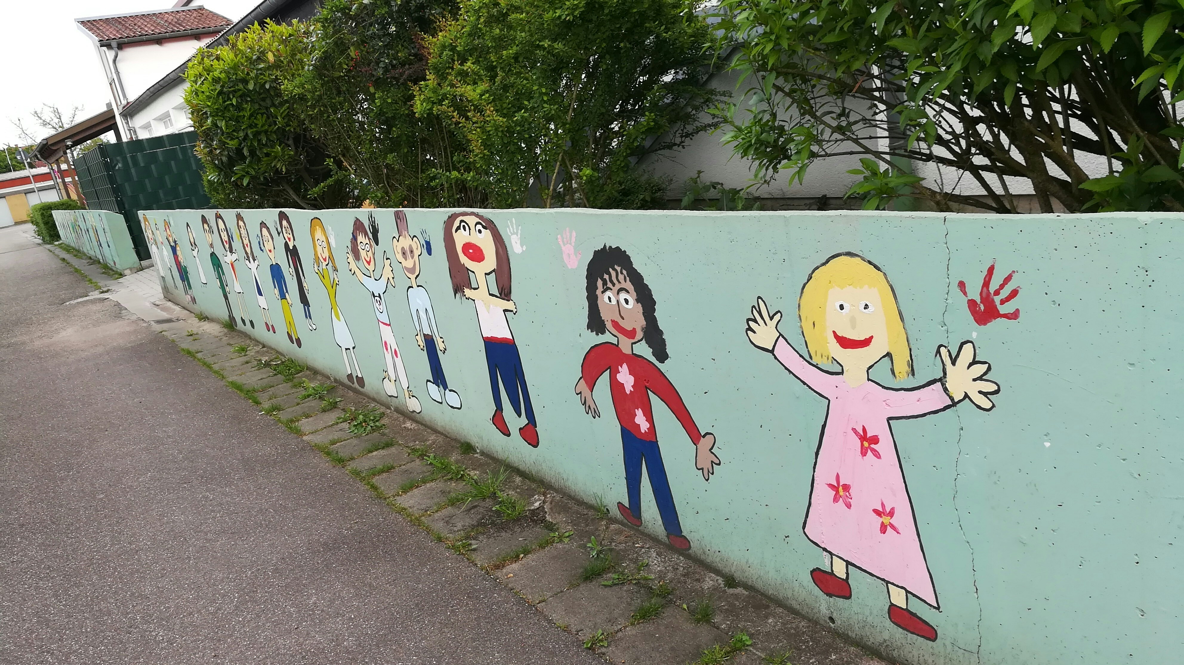 Children gathered around large nature-inspired mural on bright white wall with green botanical motifs