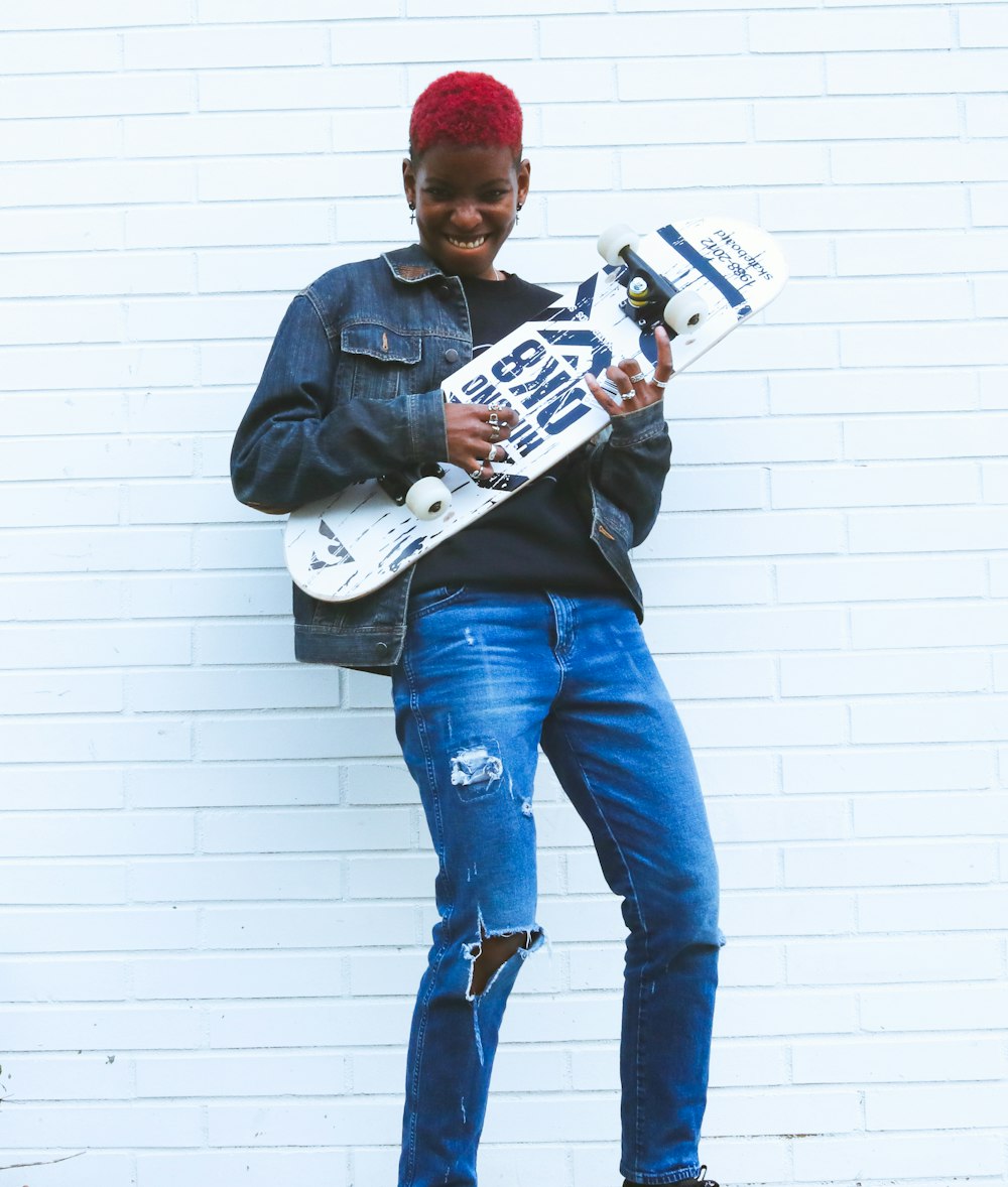 man in blue denim jacket holding white and black labeled plastic bottle