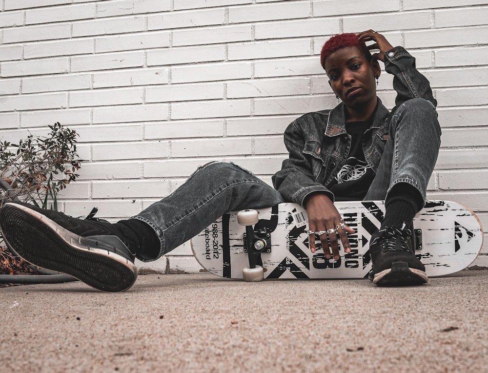 man in gray jacket and blue denim jeans sitting on brown concrete floor