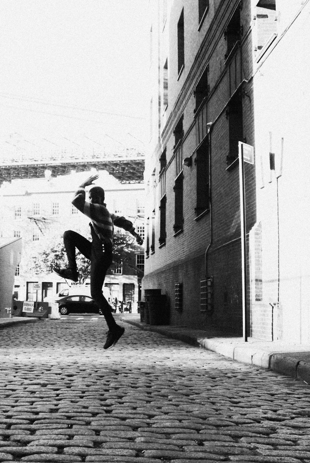 grayscale photo of woman in black tank top and pants running on street