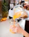 A happy woman in a bright kitchen holding a chefservz blender filled with a colorful smoothie.