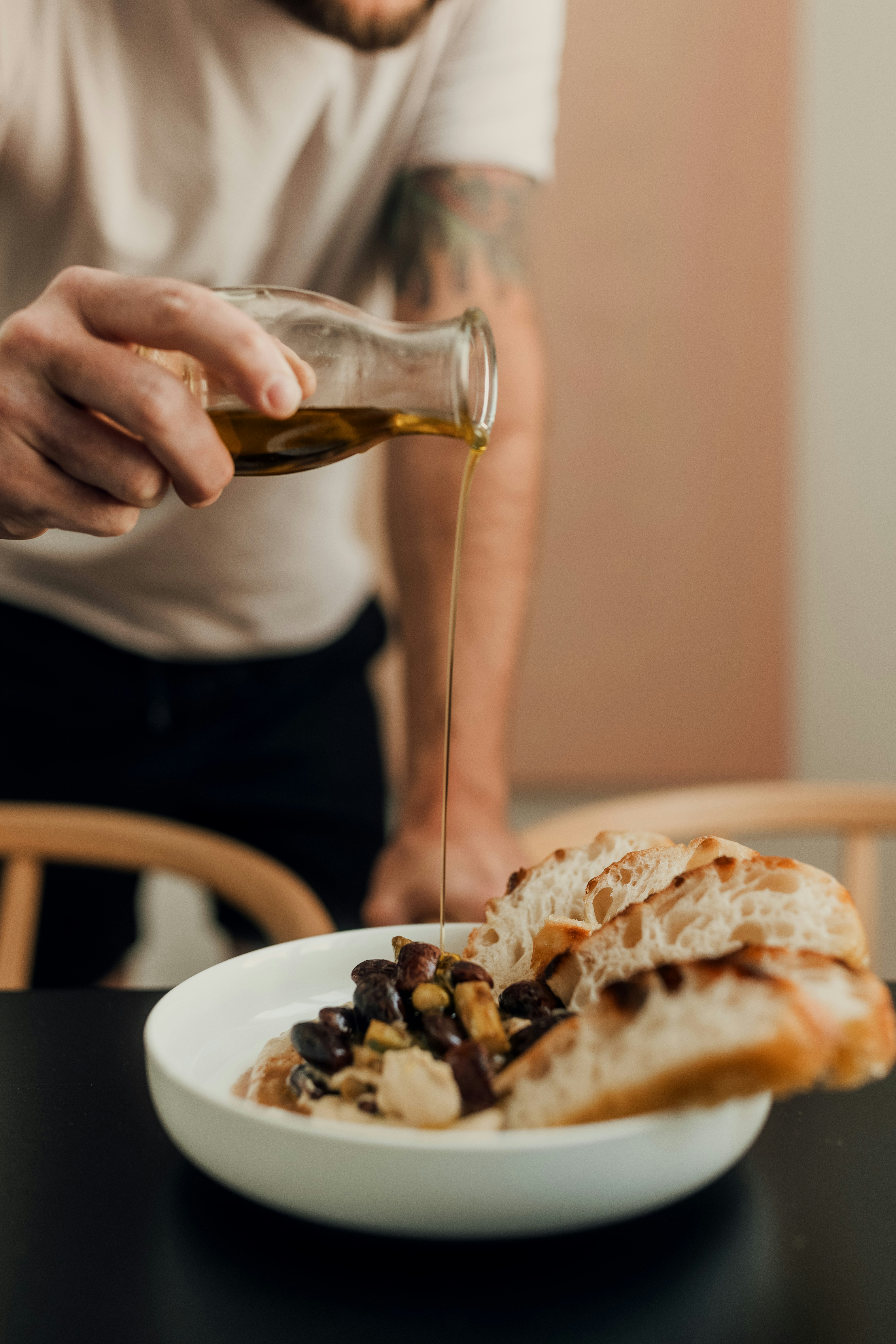 person pouring brown liquid on clear drinking glass