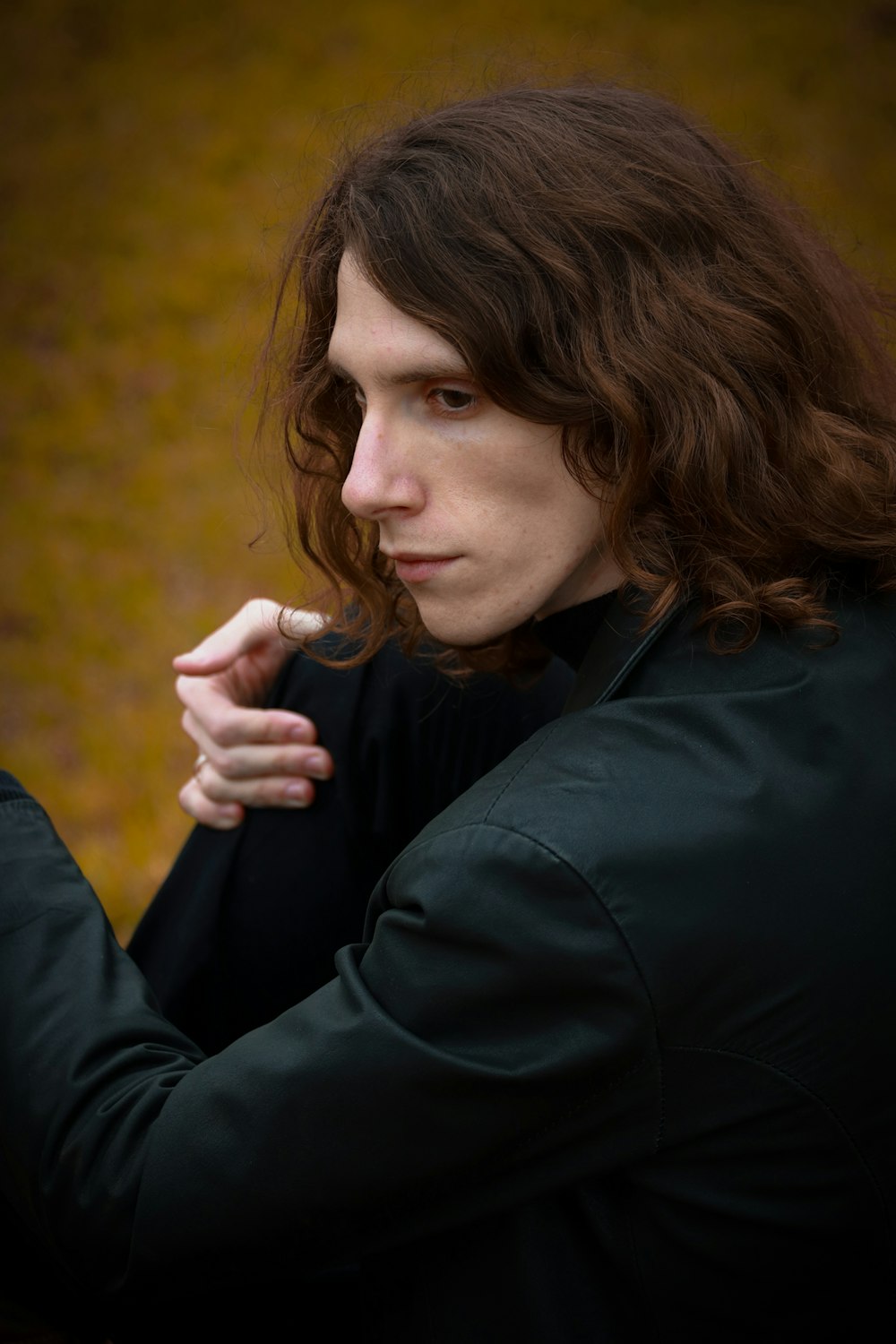 woman in black jacket holding her chin